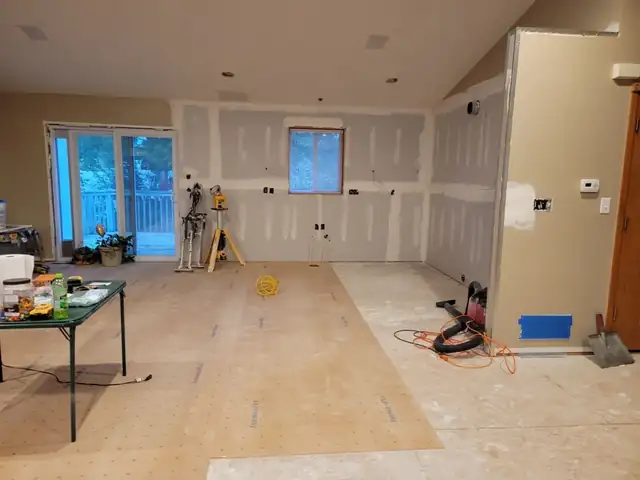 Main-level remodel in progress with new drywall, a laser level and tools on the subfloor