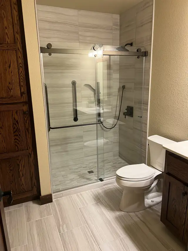Bathroom remodel with tiled walk-in shower, sliding glass door and stained wood vanity